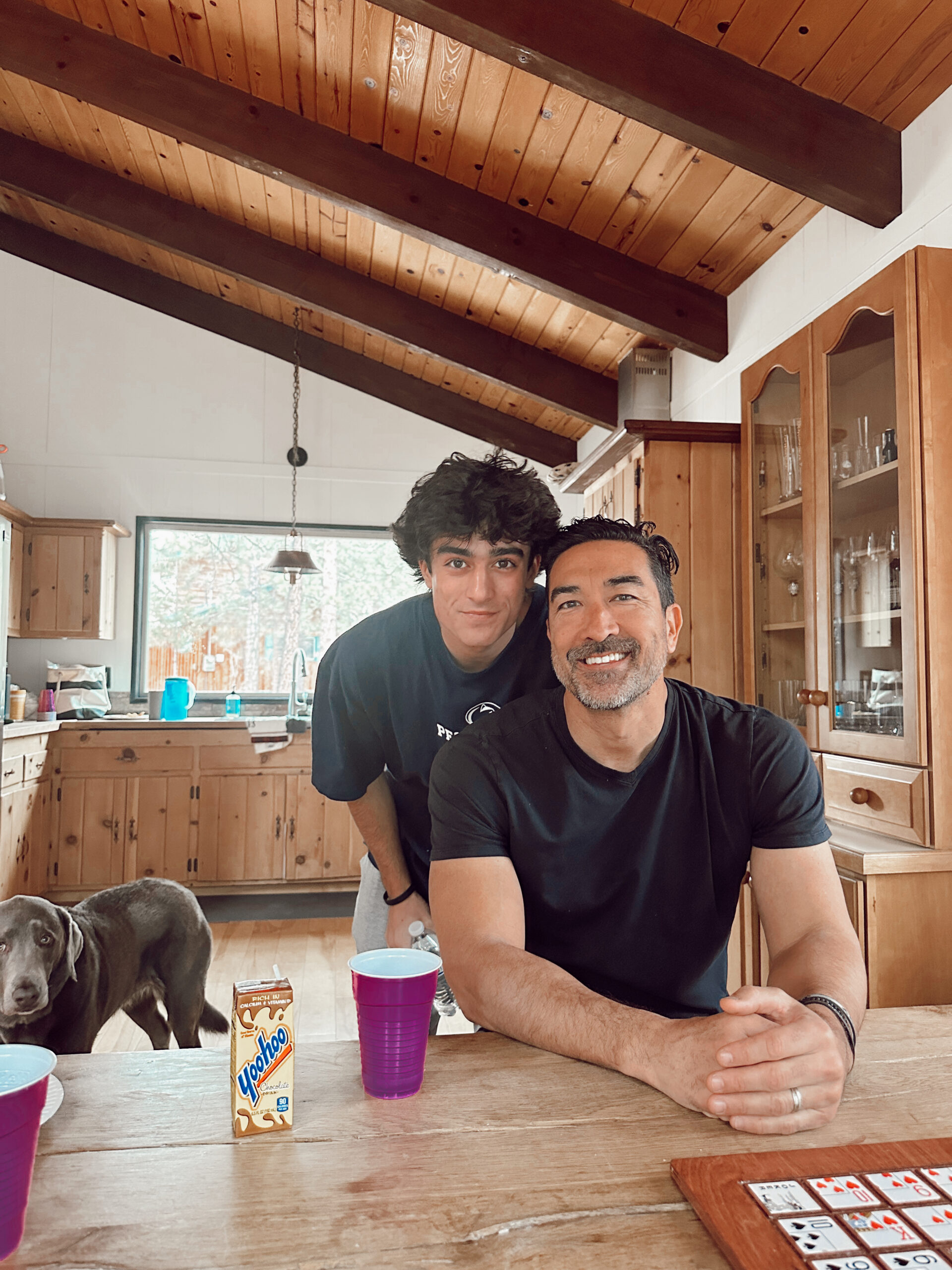 A father and son smile together at the kitchen table. 