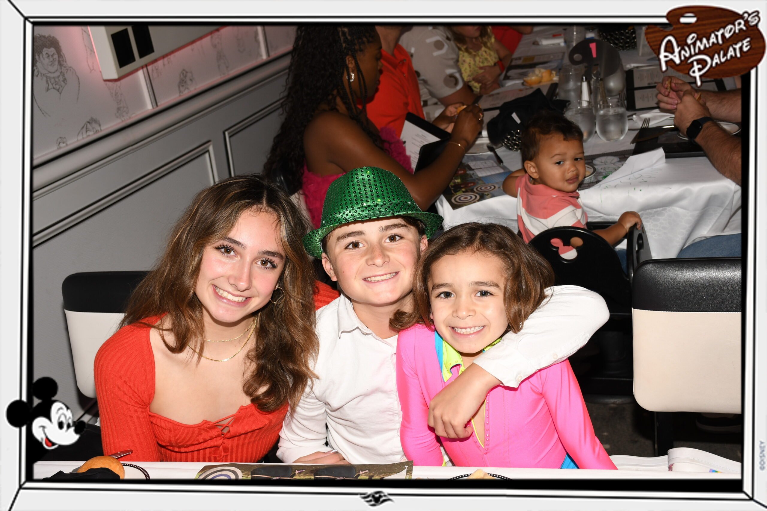 Kids in bright clothes are eating dinner at a table.