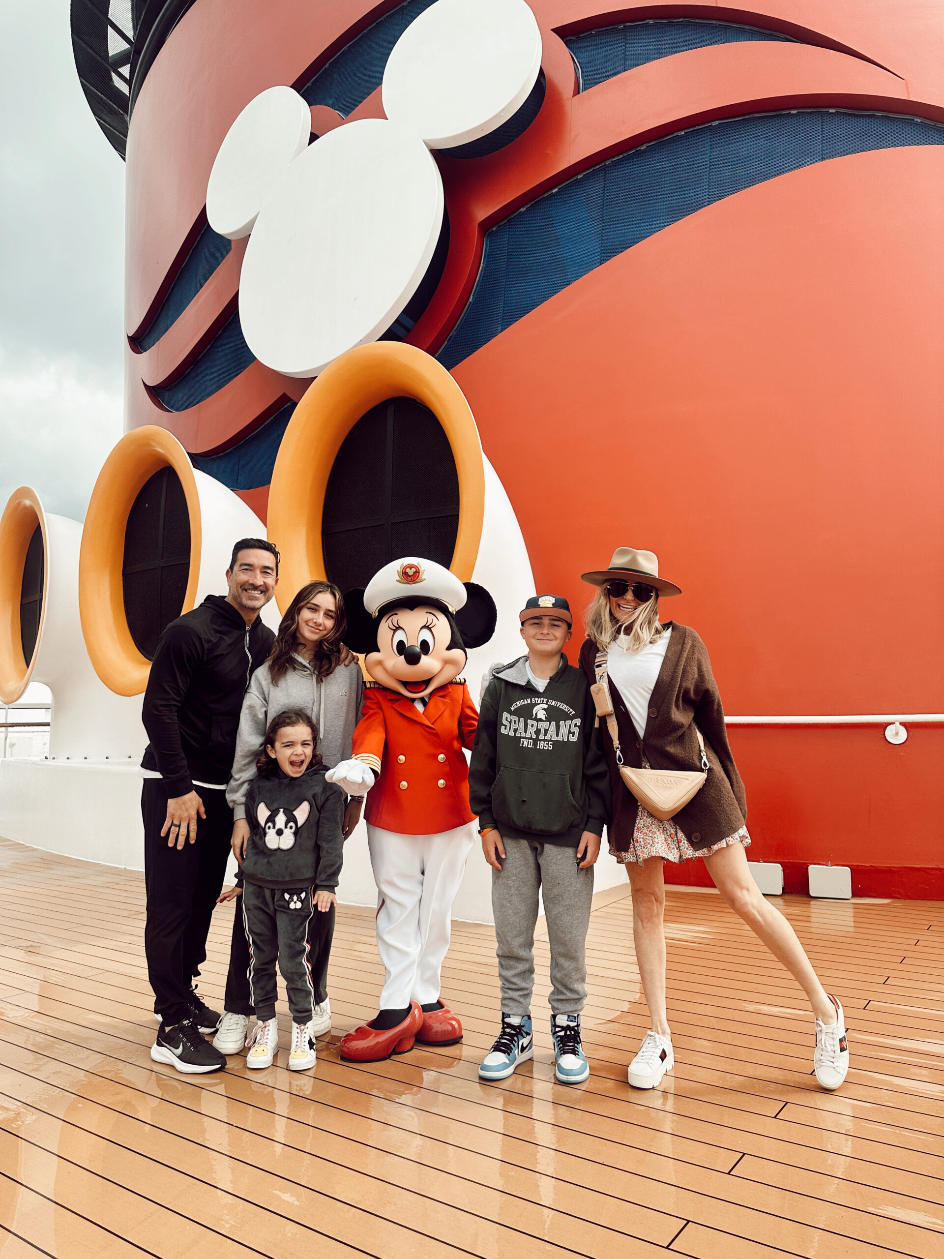 A family standing on deck with Minnie on a Disney cruise.