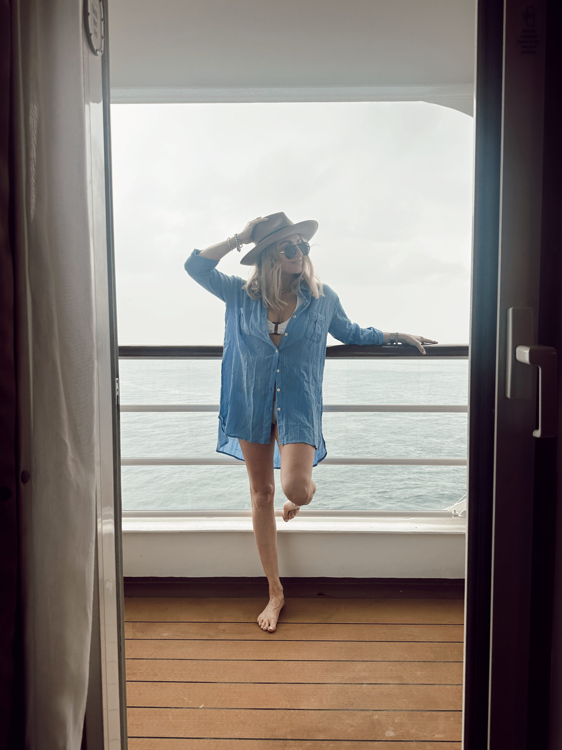 A woman leaning on the railing of her balcony on a cruise ship.