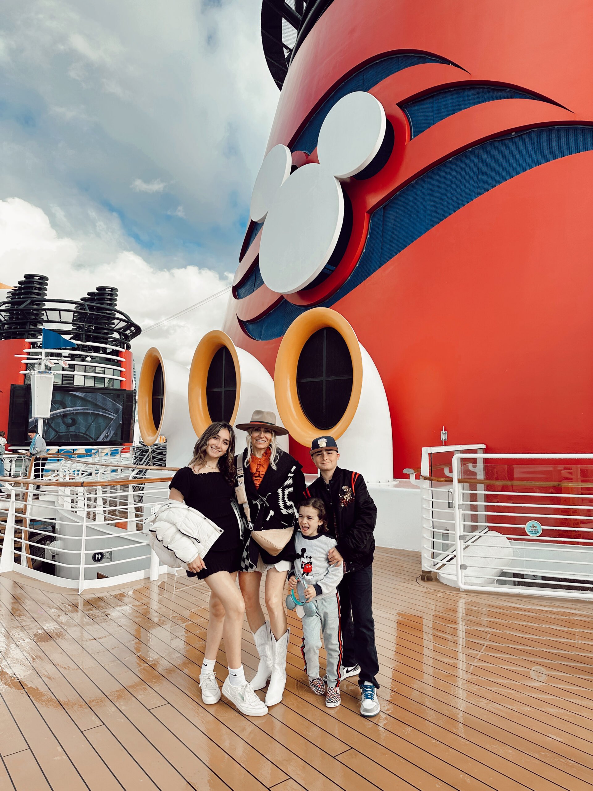 A mom and her kids posing on the deck of a Disney Cruise ship.