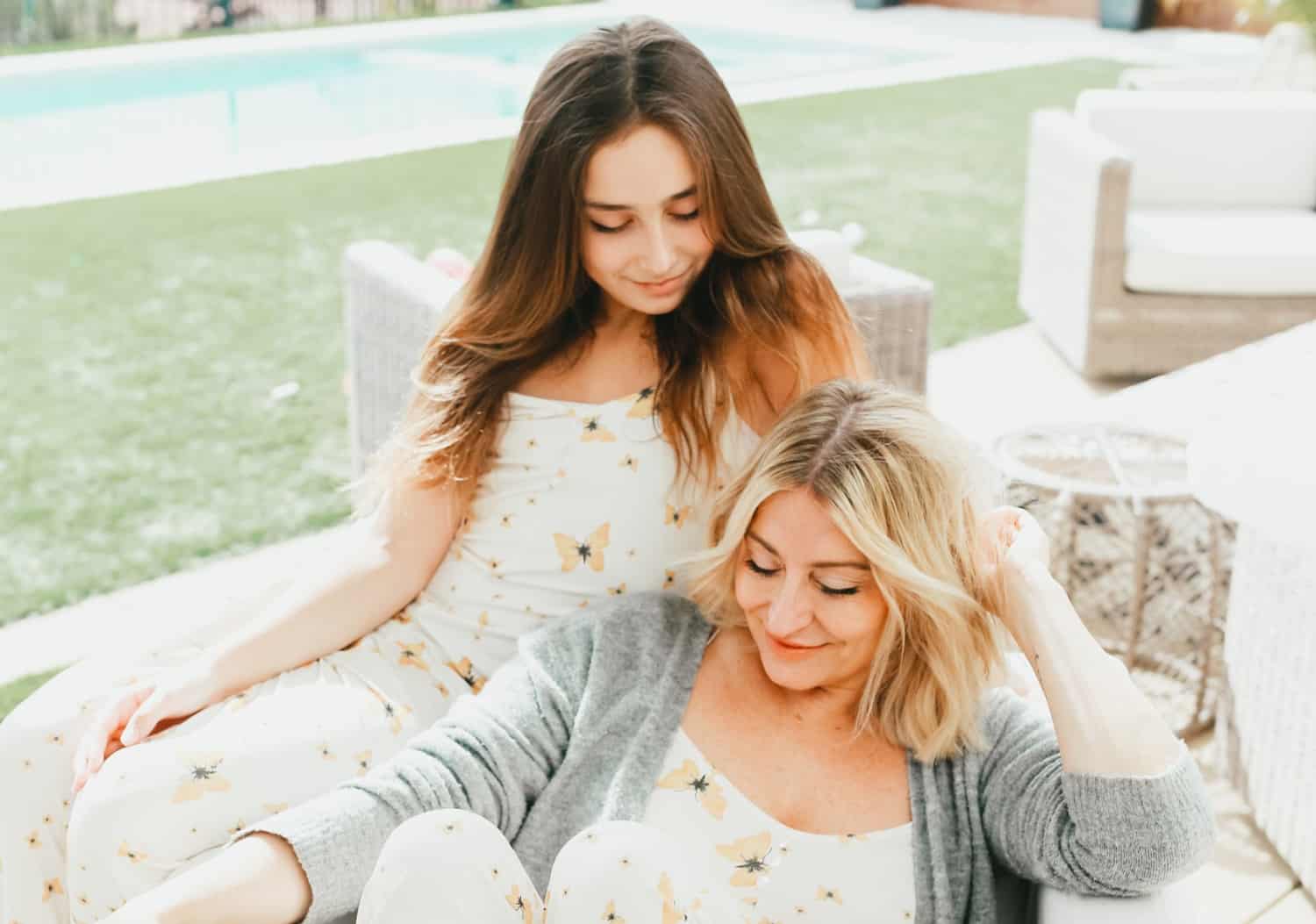 Beautiful mother and tween daughter lounging on the back patio in matching butterfly-print pajamas. 