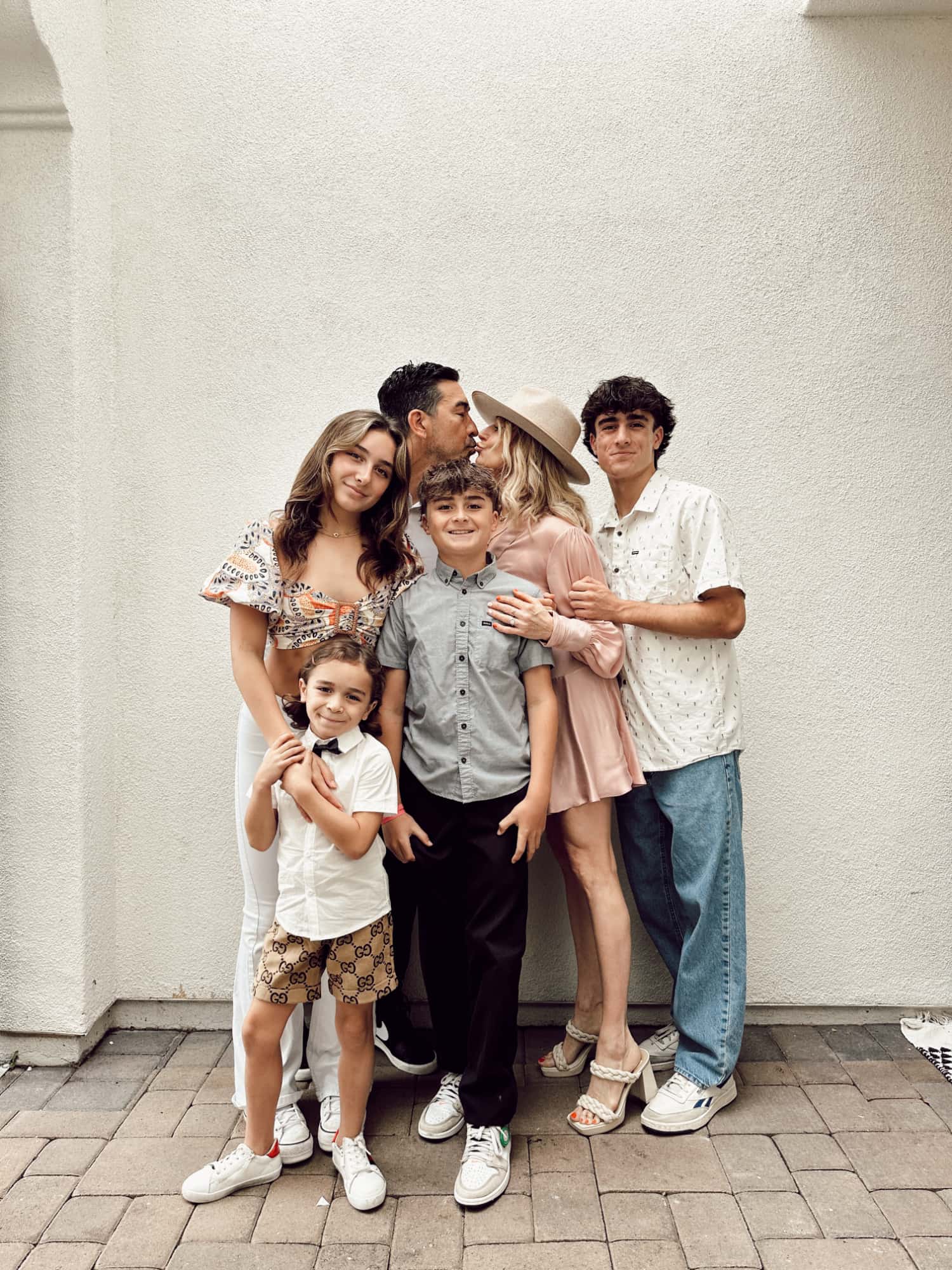 A mother and father stealing a kiss while parenting their teens and two younger boys. 