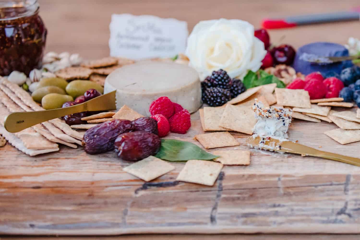 A delicious charcuterie board with cheeses, crackers, berries, and olives.