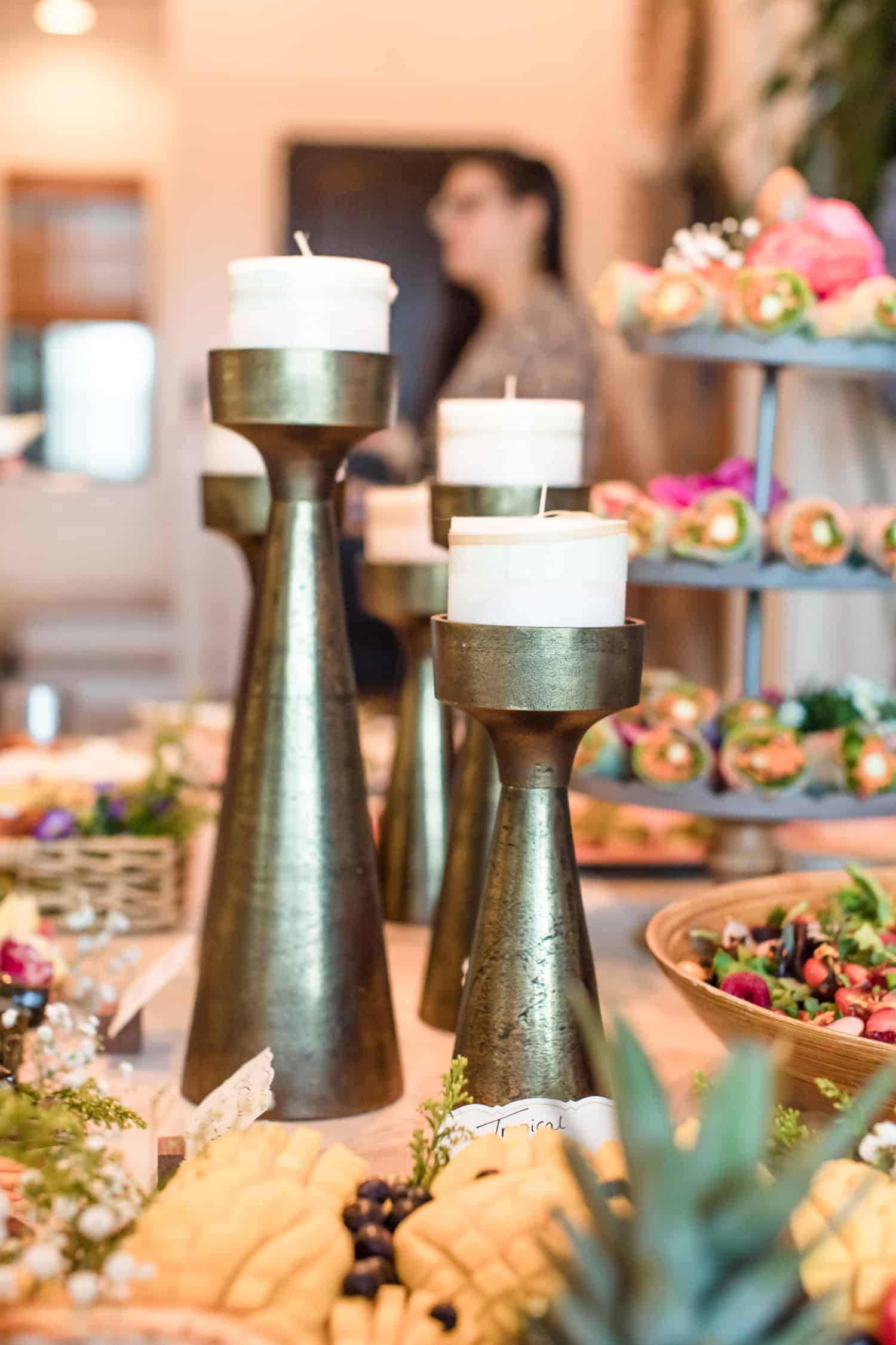 Up close image of candle sticks and a table filled with food. 