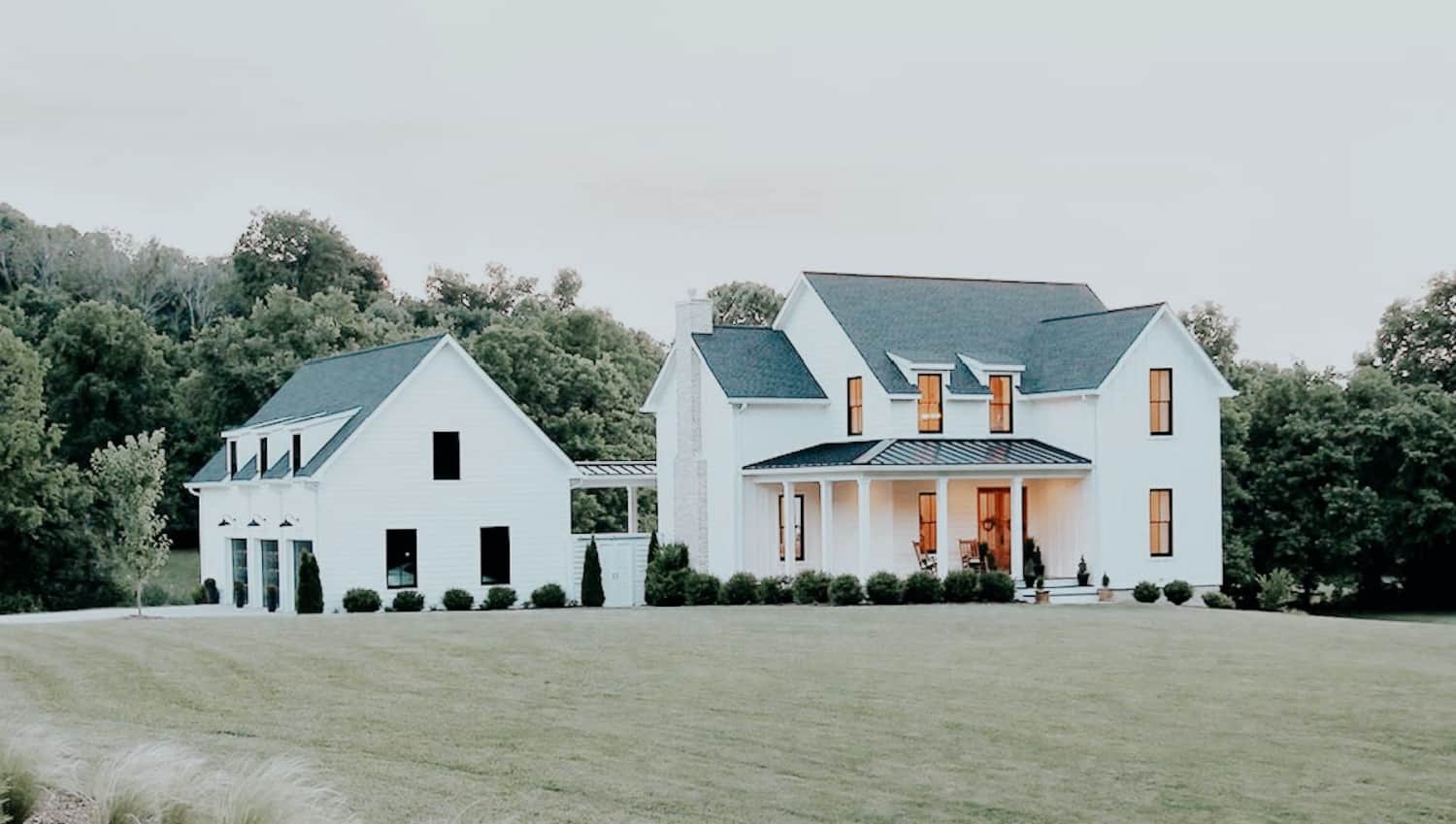 A large white modern farmhouse on a hill.