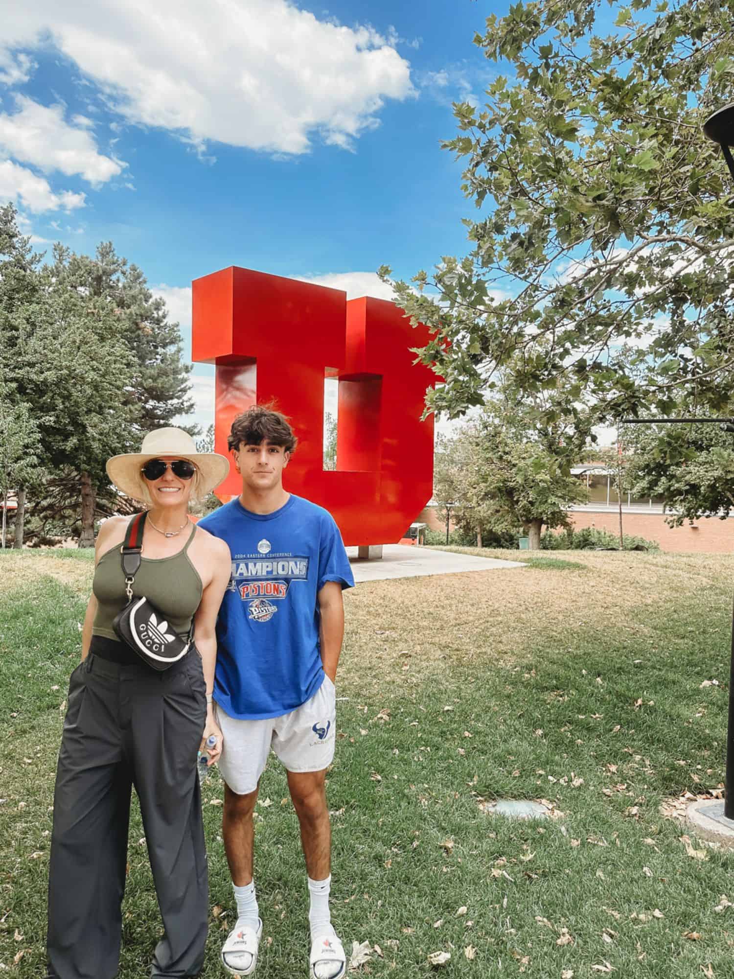 woman and boy in from of University of Utah, sign