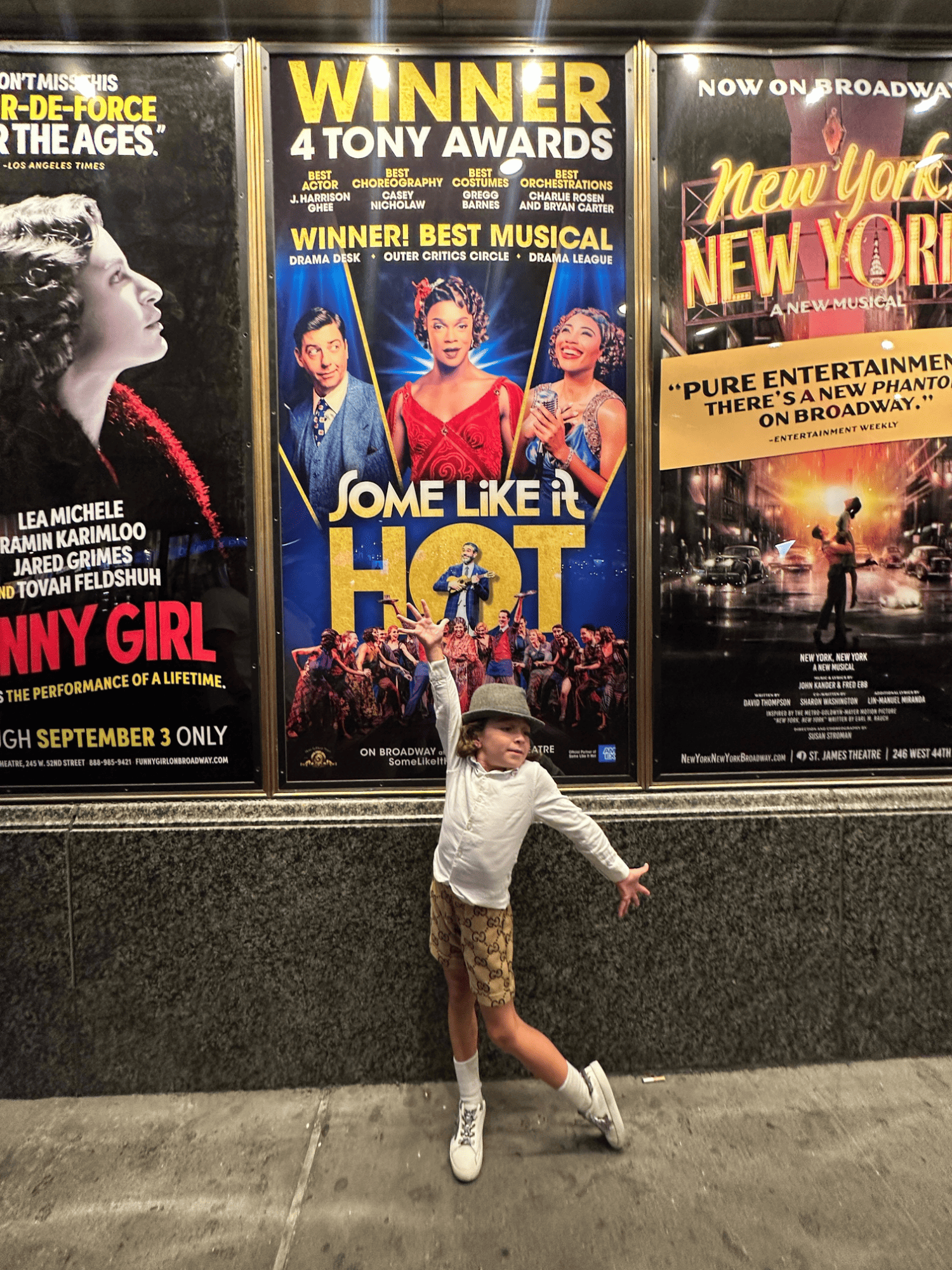 boy standing in front broadway signs 